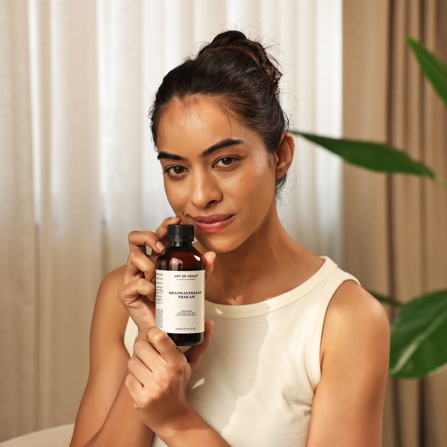 Art of Vedas Dhanwantharam Thailam - Woman Holding Ayurvedic Oil Bottle for Vata Balance and Nervous System Support