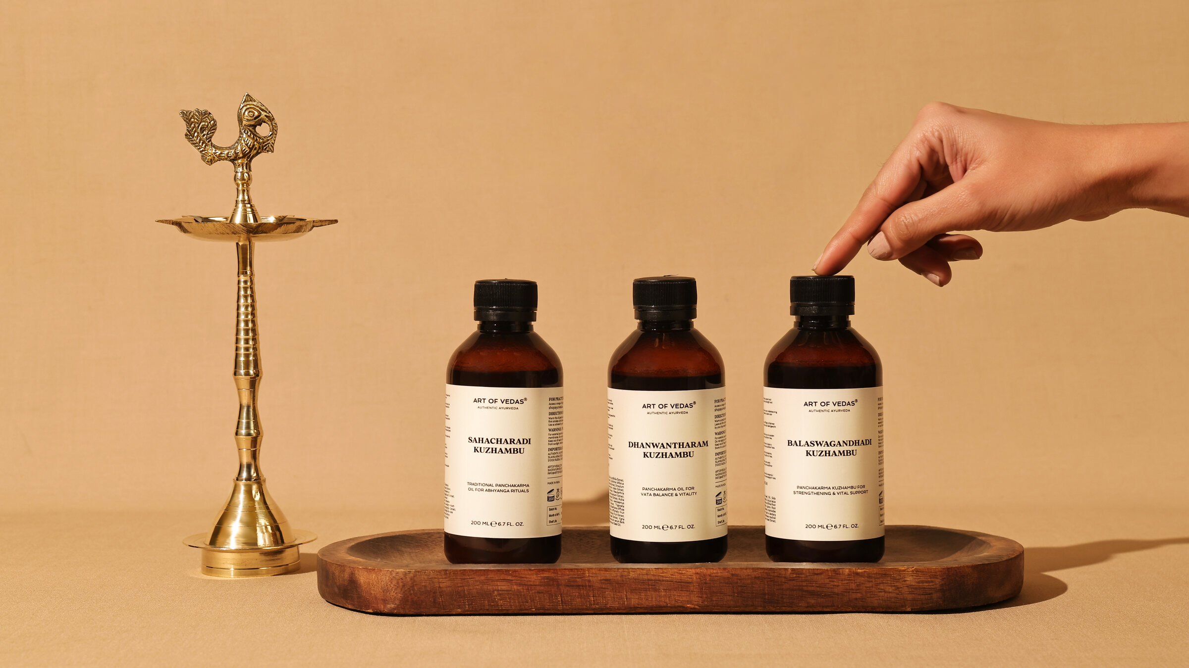 Botellas de Kuzhambu Art of Vedas con lámpara ritual de latón sobre una bandeja de madera
