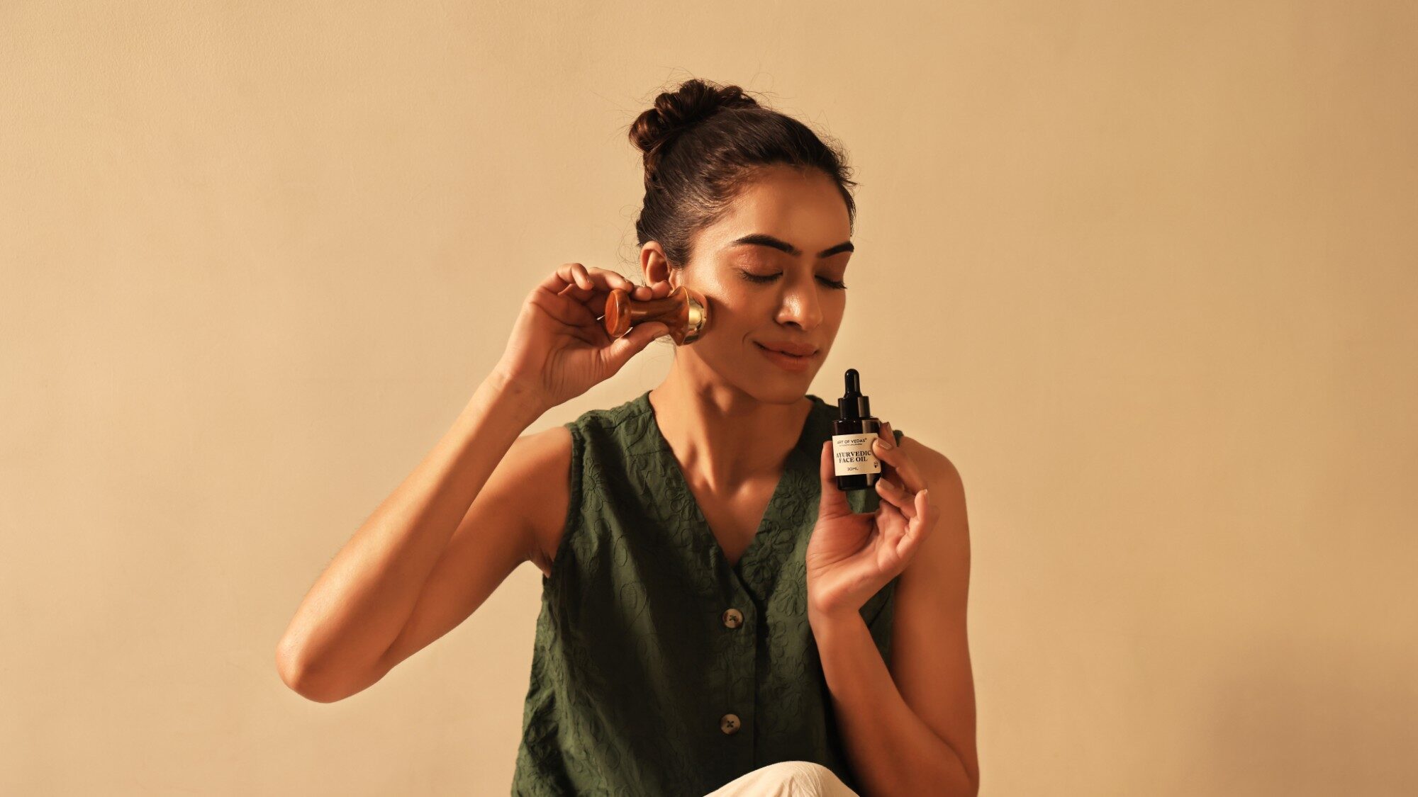 Art of Vedas Aceite facial ayurvédico junto a una herramienta Kansa de masaje facial en un ritual diario